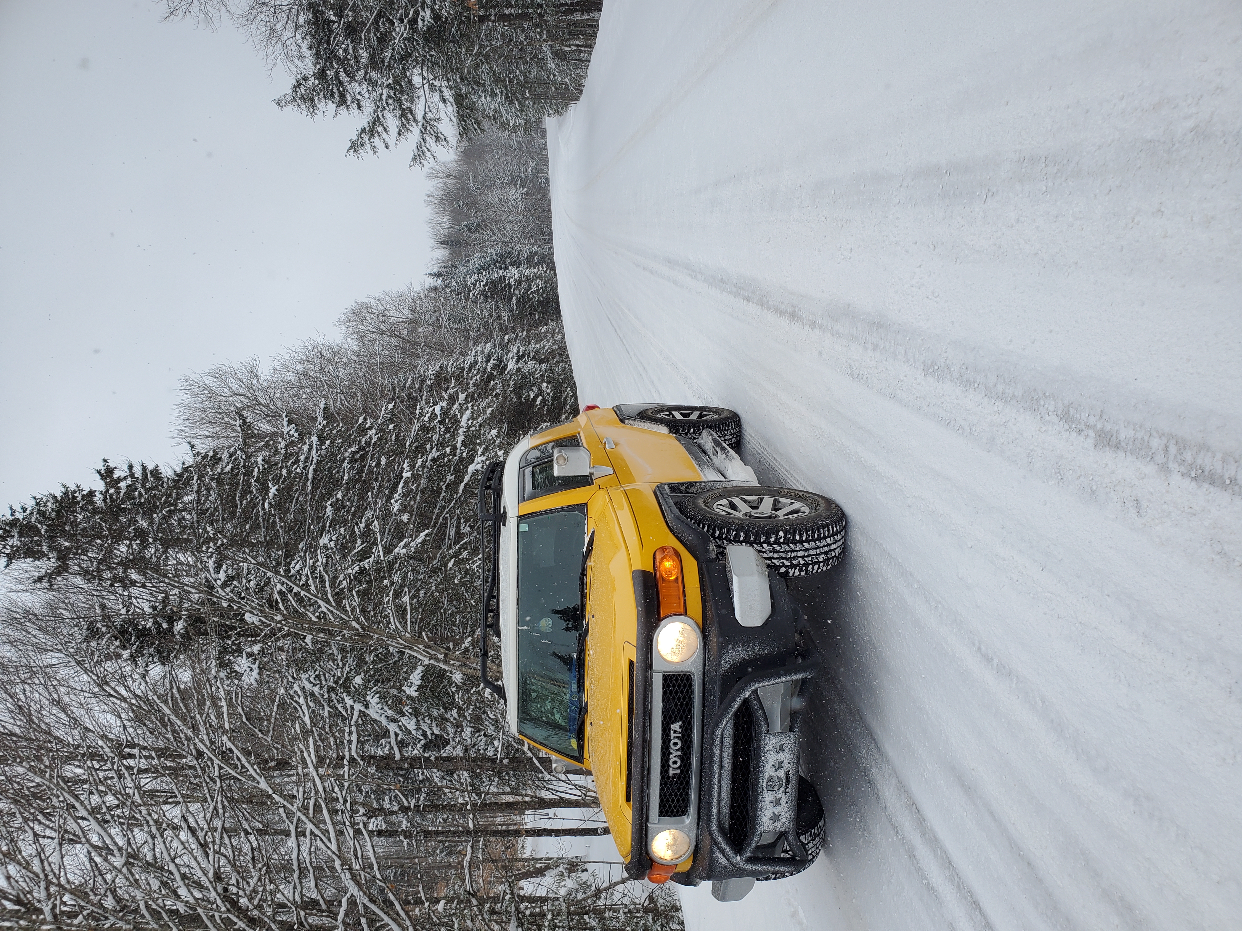 a yellow Toyota FJ cruiser on a snowy road in Michigan