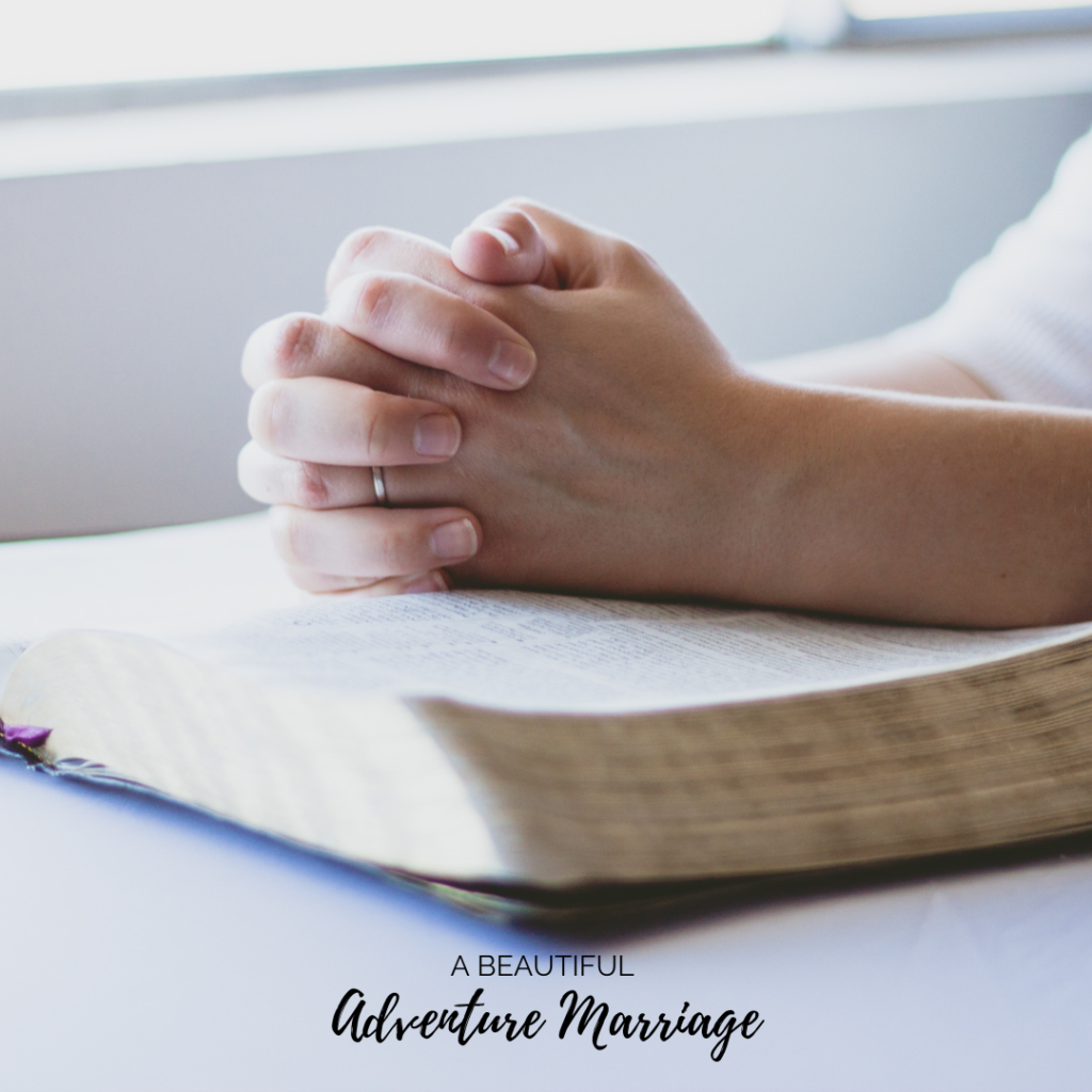 Hands clasp on an opening Bible in prayer